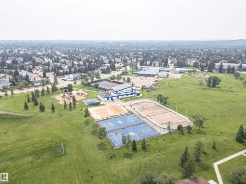 Expansive parkland with multiple recreational amenities, including a sports field, playground, basketball courts, and an outdoor rink - #61 215 Saddleback Rd Nw, Edmonton, AB - Outdoor With View