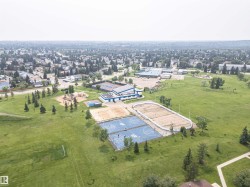 Expansive parkland with multiple recreational amenities, including a sports field, playground, basketball courts, and an outdoor rink - 
