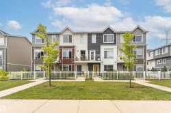 Contemporary townhome exterior featuring multi-toned siding, gabled rooflines, multiple balconies with metal railings, a yellow front door, and a white picket fence - 