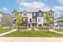Contemporary townhome exterior featuring multi-toned siding, gabled rooflines, multiple balconies with metal railings, a yellow front door, and a white picket fence - #61 215 Saddleback Rd Nw, Edmonton, AB  - Outdoor With Facade 