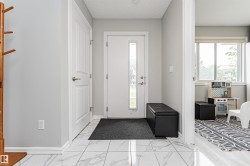 Entryway featuring large format marble-look tile flooring, a white front door with a vertical glass insert, and light gray wall paint - 
