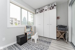 Bright room featuring a large window, light gray walls, wood-finish flooring, and a white built-in wardrobe with multiple panels - 