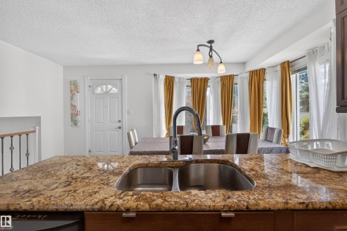 Kitchen island with a double basin stainless steel sink and granite countertop - 9007 169 Avenue Nw, Edmonton, AB - Indoor Photo Showing Kitchen With Double Sink