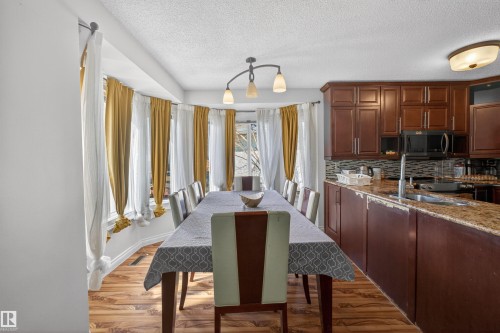 Dining area with wood-finish flooring and a bay window - 9007 169 Avenue Nw, Edmonton, AB - Indoor Photo Showing Kitchen With Double Sink