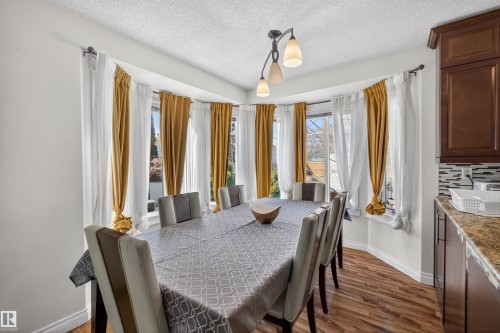 Bay window with multiple panels, wood-finish flooring, dark wood cabinetry, light-colored countertops, and a tiled backsplash - 9007 169 Avenue Nw, Edmonton, AB - Indoor Photo Showing Dining Room