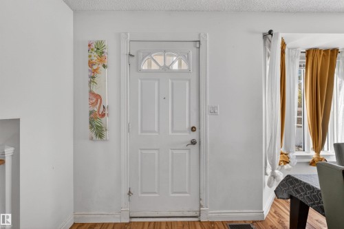 White paneled door with an arched window, wood-finish flooring, and light-toned walls - 9007 169 Avenue Nw, Edmonton, AB - Indoor Photo Showing Other Room