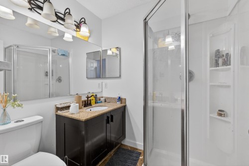 Vanity with a light-toned countertop, a single basin sink, and dark wood-finish cabinetry - 9007 169 Avenue Nw, Edmonton, AB - Indoor Photo Showing Bathroom