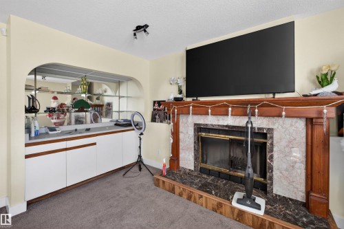 Wood-finish mantel with a marble-surround fireplace - 9007 169 Avenue Nw, Edmonton, AB - Indoor Photo Showing Living Room With Fireplace