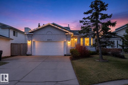 Stucco exterior with an attached garage, concrete driveway, and established front landscaping - 9007 169 Avenue Nw, Edmonton, AB - Outdoor