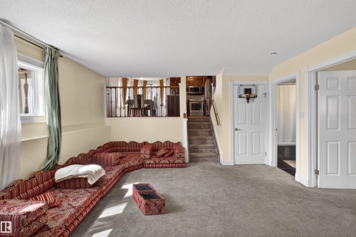 Carpeted lower level with a window, white paneled doors, and a staircase with a wood handrail - 9007 169 Avenue Nw, Edmonton, AB - Indoor