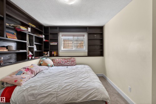 Built-in shelving, window with horizontal blinds, neutral wall paint, white trim, and carpeted flooring - 9007 169 Avenue Nw, Edmonton, AB - Indoor Photo Showing Bedroom