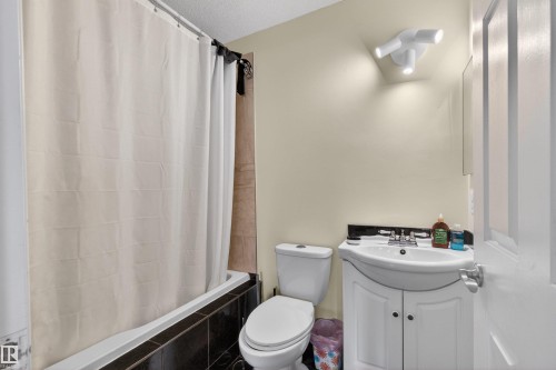 White vanity with integrated sink, chrome faucet, and dark countertop - 9007 169 Avenue Nw, Edmonton, AB - Indoor Photo Showing Bathroom