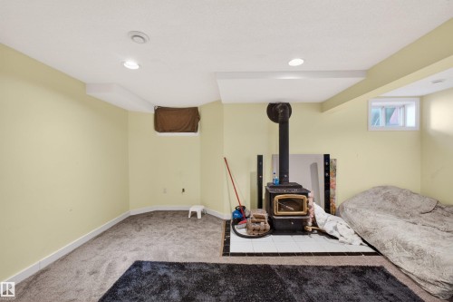 Recessed lighting, wood-burning stove with a tiled hearth, and carpeted flooring - 9007 169 Avenue Nw, Edmonton, AB - Indoor