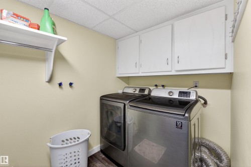 Laundry area featuring white cabinetry, a hanging rack, and wood-finish flooring - 9007 169 Avenue Nw, Edmonton, AB - Indoor Photo Showing Laundry Room