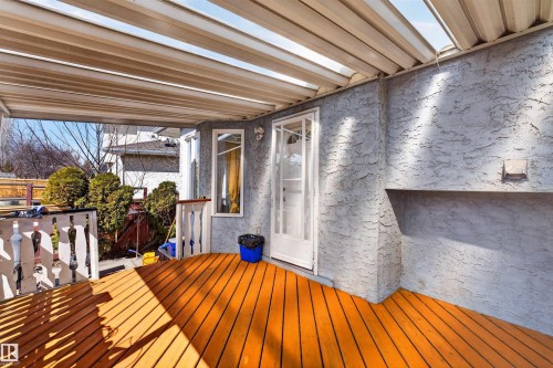 Covered outdoor deck with wood flooring and a textured stucco wall - 9007 169 Avenue Nw, Edmonton, AB - Outdoor With Deck Patio Veranda