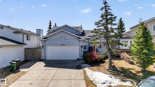 Front exterior with an attached garage, paved driveway, and mature landscaping - 9007 169 Avenue Nw, Edmonton, AB - Outdoor