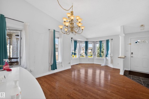 Vaulted ceiling, hardwood flooring, bay window, chandelier, and a front entry door with transom window - 9007 169 Avenue Nw, Edmonton, AB - Indoor Photo Showing Other Room