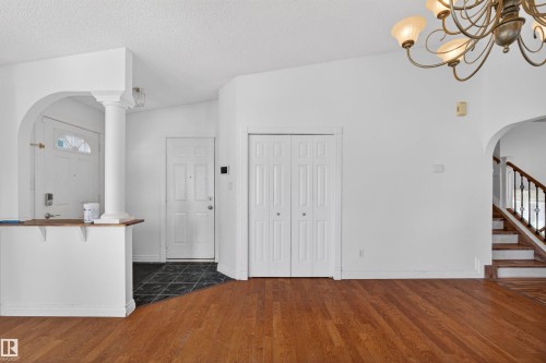 Vaulted ceiling, wood-finish flooring, staircase with wood handrail and wrought iron spindles, architectural archway, and overhead chandelier - 9007 169 Avenue Nw, Edmonton, AB - Indoor Photo Showing Other Room