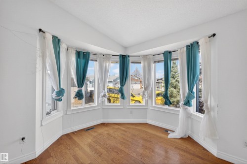 Bay window with multiple panes, hardwood flooring, and white painted walls - 9007 169 Avenue Nw, Edmonton, AB - Indoor Photo Showing Other Room
