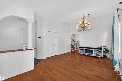 Hardwood-finish flooring, built-in bi-fold closet, recessed archway, ornate chandelier, and white wall finishes - 9007 169 Avenue Nw, Edmonton, AB - Indoor Photo Showing Other Room