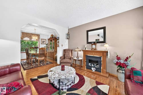 Hardwood flooring throughout, a decorative fireplace, and an arched entry to the dining area - 13069 37 Street Nw, Edmonton, AB - Indoor Photo Showing Living Room With Fireplace