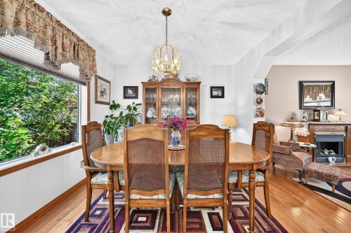 Hardwood flooring, recessed ceiling, large window, built-in display cabinetry, and an ornate chandelier - 13069 37 Street Nw, Edmonton, AB - Indoor Photo Showing Dining Room