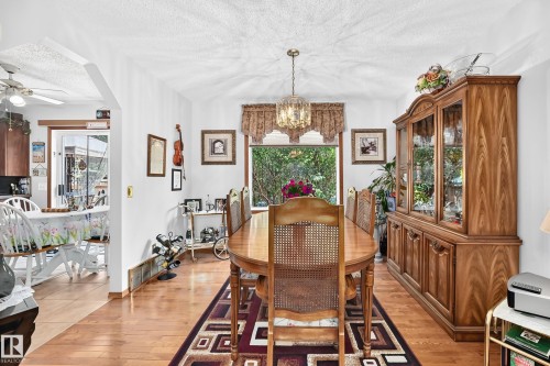 Dining area with wood-finish flooring, a built-in display cabinet, and a decorative chandelier - 13069 37 Street Nw, Edmonton, AB - Indoor Photo Showing Dining Room