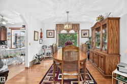 Dining area with wood-finish flooring, a built-in display cabinet, and a decorative chandelier - 