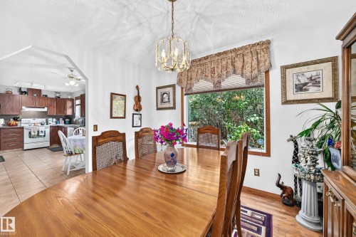 Dining area with wood-finish flooring, a large window, and an overhead decorative light fixture - 13069 37 Street Nw, Edmonton, AB - Indoor Photo Showing Dining Room