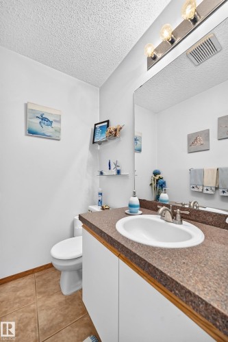 Vanity with a white sink, brushed nickel faucet, large wall mirror, and a full toilet - 13069 37 Street Nw, Edmonton, AB - Indoor Photo Showing Bathroom