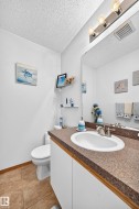 Vanity with a white sink, brushed nickel faucet, large wall mirror, and a full toilet - 