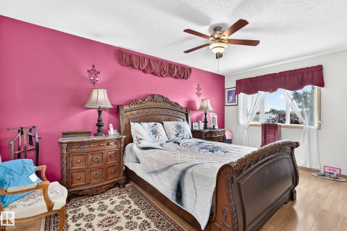 Wood-finish flooring with a ceiling fan light fixture and a window with white trim - 13069 37 Street Nw, Edmonton, AB - Indoor Photo Showing Bedroom