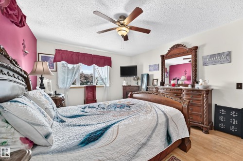 Wood-finish flooring, ceiling fan with integrated lighting, window with trim, and a built-in wall mirror - 13069 37 Street Nw, Edmonton, AB - Indoor Photo Showing Bedroom