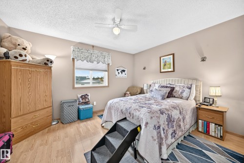 Wood-finish flooring throughout, featuring a single window with blinds and valance, a ceiling fan with integrated lighting, and neutral wall paint - 13069 37 Street Nw, Edmonton, AB - Indoor Photo Showing Bedroom