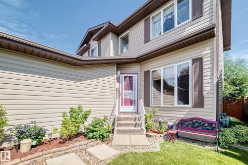 Two-story exterior with light-toned horizontal siding, brown trim, and a white front entry door with a storm door - 13069 37 Street Nw, Edmonton, AB - Outdoor