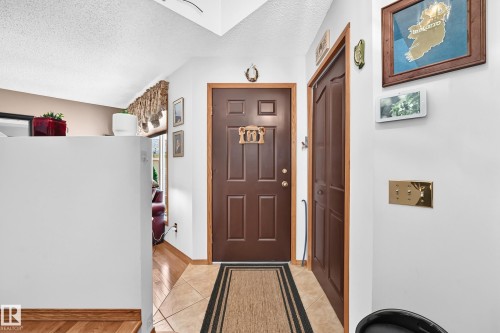 Entryway featuring a paneled door, tiled flooring, wood-finish flooring, and white walls - 13069 37 Street Nw, Edmonton, AB - Indoor Photo Showing Other Room
