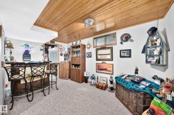 Wood-paneled ceiling, built-in bar, wood cabinetry, and neutral carpeting - 