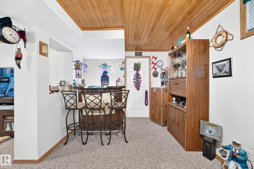 Wood-finish planked ceiling, light neutral carpet, and a wood-finish built-in bar with bar seating - 13069 37 Street Nw, Edmonton, AB - Indoor Photo Showing Other Room