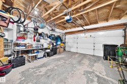 Concrete flooring, exposed ceiling joists, overhead lighting, and a white panel garage door - 