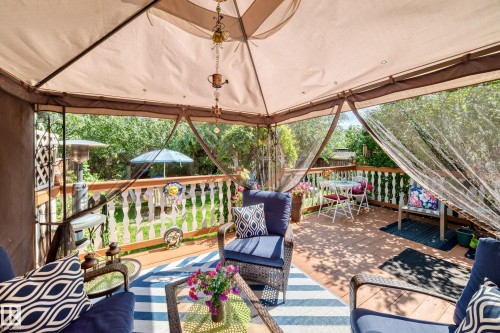 Covered outdoor patio with a full fabric canopy, wood-finish flooring, and white baluster railing - 13069 37 Street Nw, Edmonton, AB - 