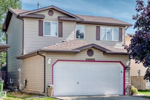 Two-story residence featuring light-toned horizontal siding, dark brown roofing, and a prominent double garage with a white door - 13069 37 Street Nw, Edmonton, AB - Outdoor With Exterior
