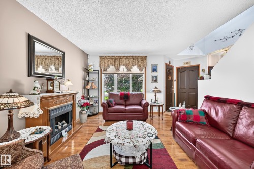 Living area featuring wood-finish flooring, a built-in fireplace with an ornate wooden mantel, and a large window with valance - 13069 37 Street Nw, Edmonton, AB - Indoor Photo Showing Living Room With Fireplace