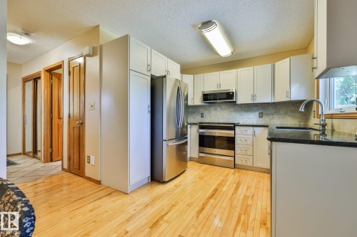 The newer kitchen showcases refaced cabinetry, granite countertops, designer tile backsplash and quality stainless steel appliances, complemented by birch hardwood flooring. - 3764 30 Street Nw, Edmonton, AB - Indoor Photo Showing Kitchen