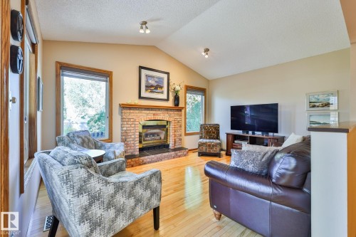 Convenient main floor family room with vaulted ceiling, brick facing reconditioned gas fireplace, birch hardwood flooring and access to your massive deck - 3764 30 Street Nw, Edmonton, AB - Indoor Photo Showing Living Room With Fireplace