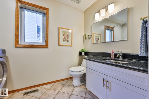 Spacious combined main floor bath & laundry room.  Notice the granite tops, refaced cabinets and ceramic tile flooring - 3764 30 Street Nw, Edmonton, AB - Indoor Photo Showing Bathroom