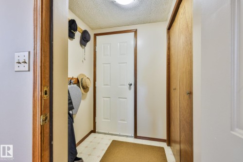 Unique back entry from the garage features a paneled door, wood-finish trim, patterned flooring, and built-in closet with bi-fold doors - 3764 30 Street Nw, Edmonton, AB - Indoor Photo Showing Other Room