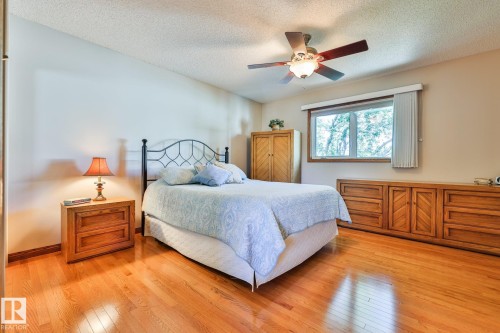 The large primary bedroom offers Hardwood flooring, mirrored closet doors, ceiling fan with integrated lighting, and a large window - 3764 30 Street Nw, Edmonton, AB - Indoor Photo Showing Bedroom