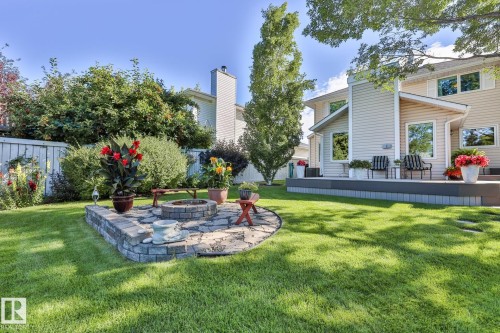 Expansive green lawn, a stone-bordered fire pit with a flagstone base, and a multi-level deck - 3764 30 Street Nw, Edmonton, AB - Outdoor With Deck Patio Veranda