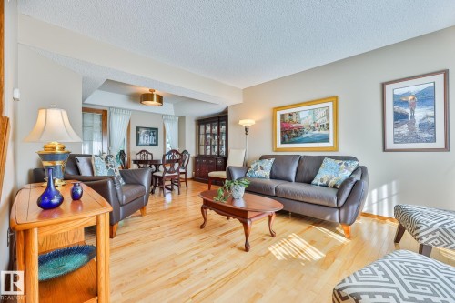 Birch Hardwood flooring throughout, recessed ceiling detail, and an attached dining area with a brass-finish chandelier - 3764 30 Street Nw, Edmonton, AB - Indoor Photo Showing Living Room