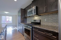 Kitchen featuring dark wood-finish cabinetry, stainless steel appliances, granite countertops, and a glass tile backsplash - 